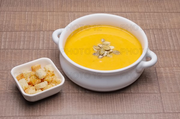 Plate with pumpkin soup with seeds and crackers