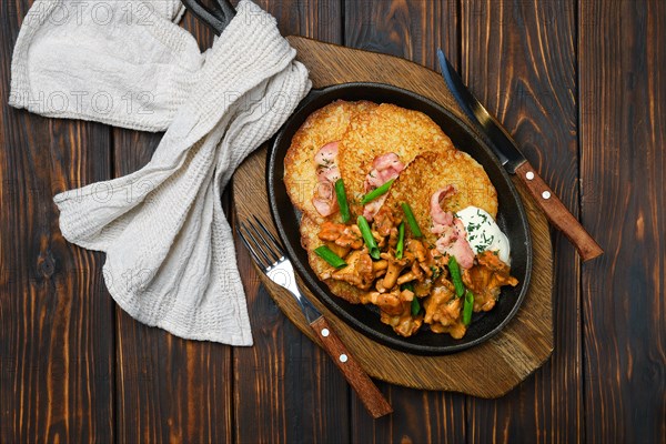 Top view of potato pancakes with chanterelles and pork in cast iron skillet