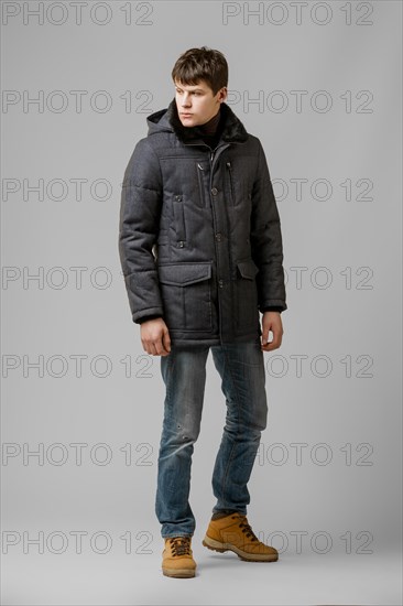 Full length portrait of handsome man in warm winter coat posing in studio