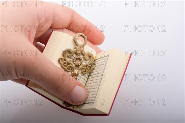 Hand holding Key and Islamic Holy Book Quran in mini size