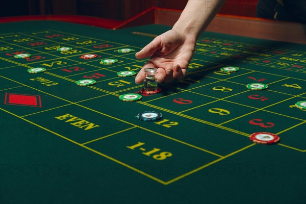 Casino roulette table with chips and cards. Winning combination. Hand of Croupier behind gambling table