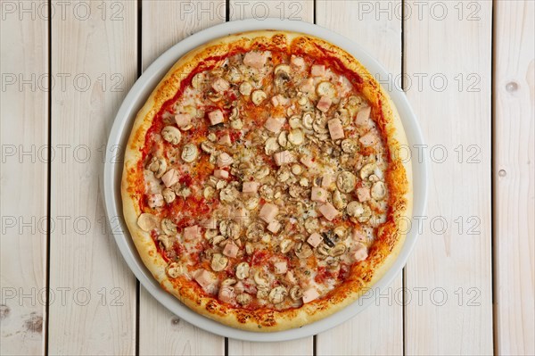 Top view of pizza with ham and champignon on wooden table