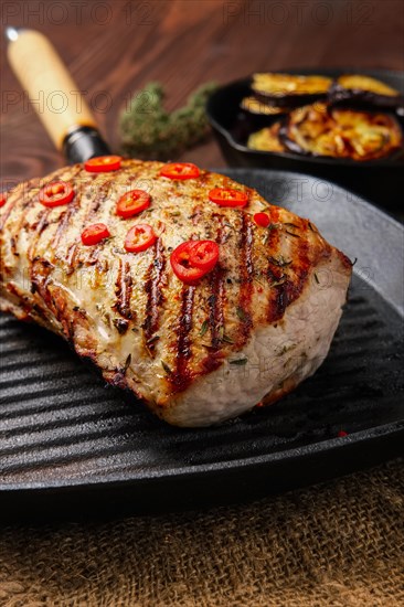 Grilled striploin on cast iron skillet and fried eggplant on wooden background