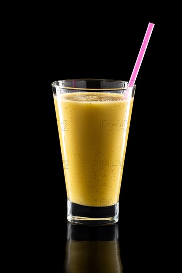 Glass of fresh cold smoothies with straw isolated on black background