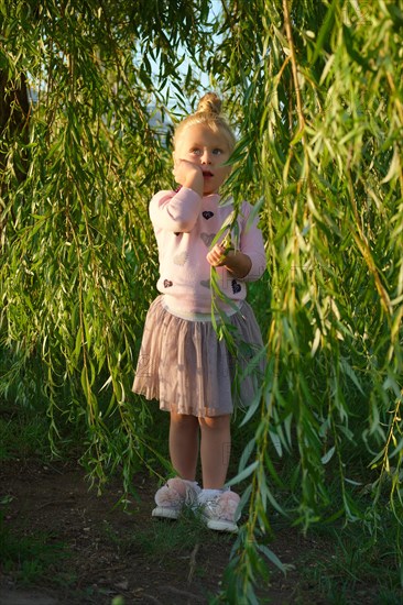 Cute little child under willow tree in park
