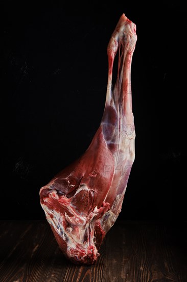 Raw hind quarter of deer leg over dark background