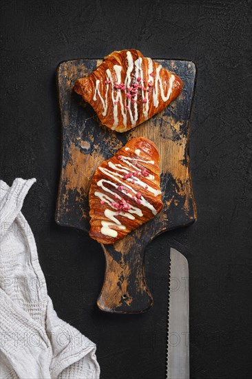 Top view of crispy croissant with raspberry on wooden serving board