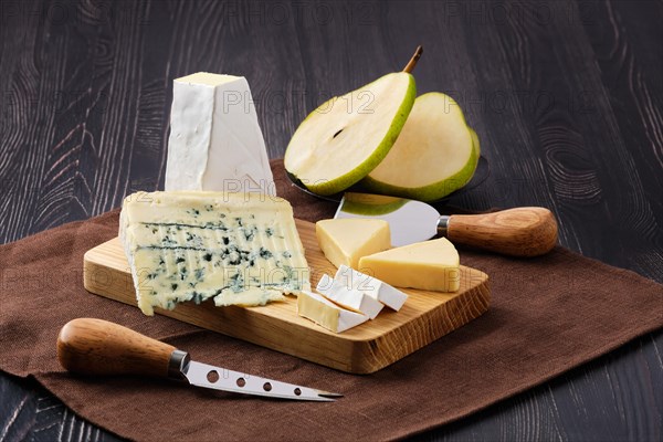 Assortment of cheese and snack for wine on dark wooden table