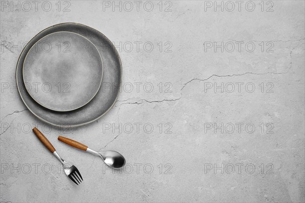 Overhead view of two plates and fork with spoon on concrete background