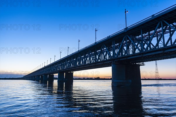 Giant bridge spanning over the Amur river at sunset