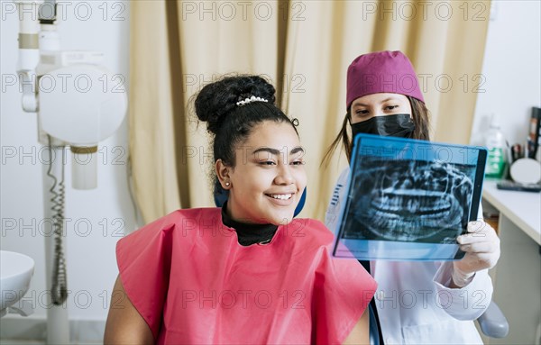 Dentist with patient reviewing the x-ray. Patient looking at x-ray with dentist