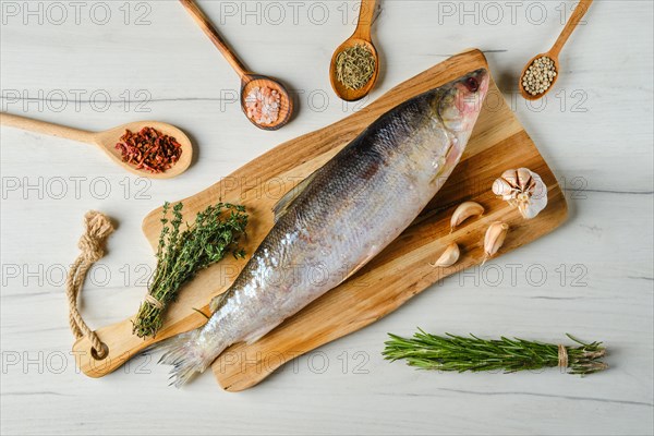 Overhead view of raw frozen unpeeled omul on wooden cutting board