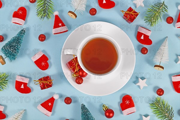 Tea cup surrounded by seasonal Christmas decoration on blue background