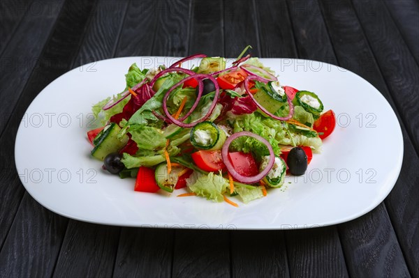 Salad with feta cheese rolled in cucumber slices with tomato and red onion