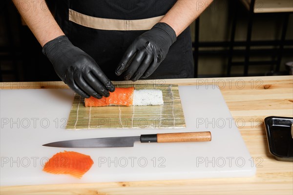 Chef puts salmon while preparing rolls