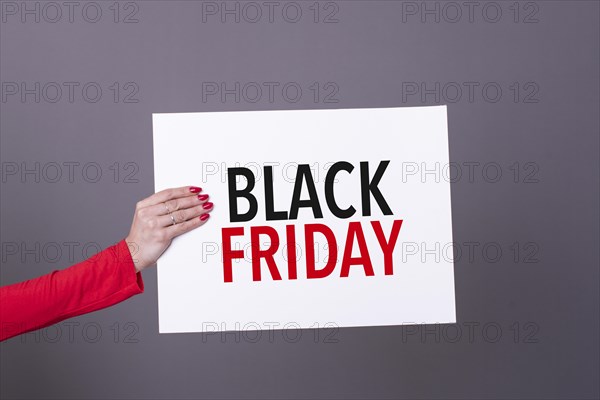 Female hand holding a black friday poster. Studio shot