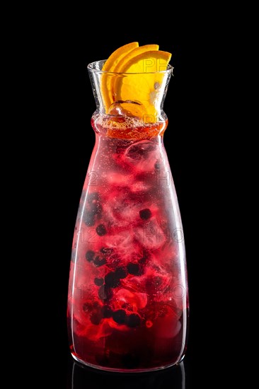 Pitcher with black currant and orange ice lemonade isolated on black background