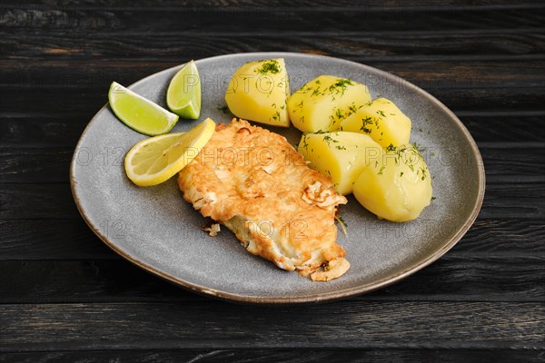 Plate with fried cod steak in cheese breading fried with boiled potato