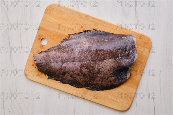 Top view of raw fresh halibut without head on wooden cutting board