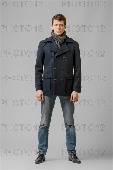 Full length portrait of handsome man in warm woolen coat posing in studio