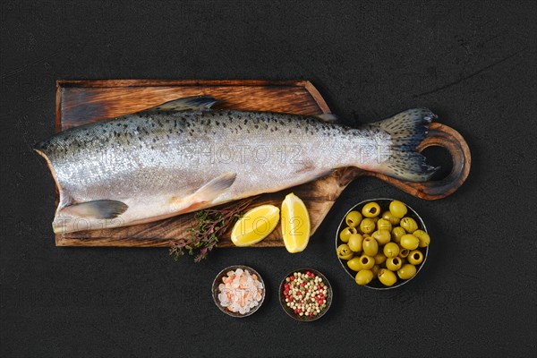 Headless fresh chinook on wooden cutting board with spice and lemon