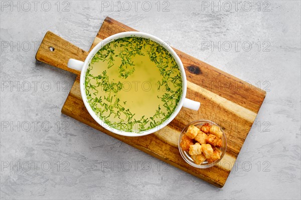 Top view of chicken stock with croutons on wooden serving board