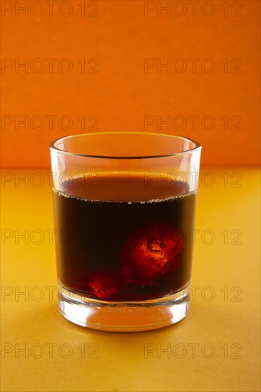 Cola with ice on orange background