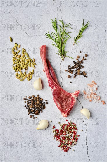 Composition with raw doe ribs with spice and herb over concrete background