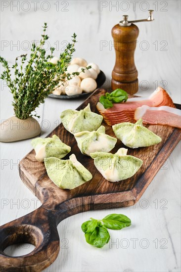 Dumplings stuffed with smoked ham and mushrooms on wooden serving board