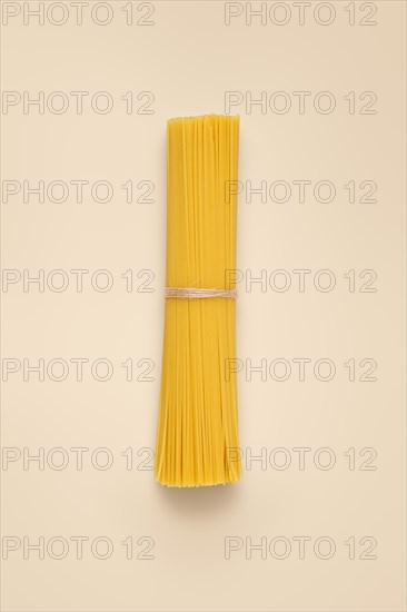 Bunch of spaghetti tied with twine over light beige background