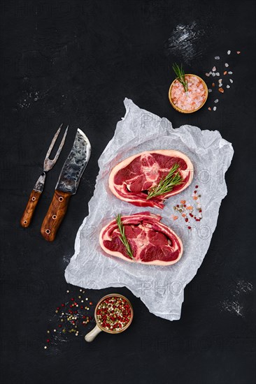 Fresh raw rack of lamb on wooden cutting board with herbs and seasoning