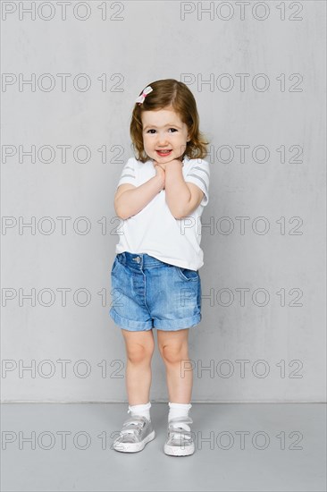 Two years old girl in white t-short and jeans shorts posing in studio