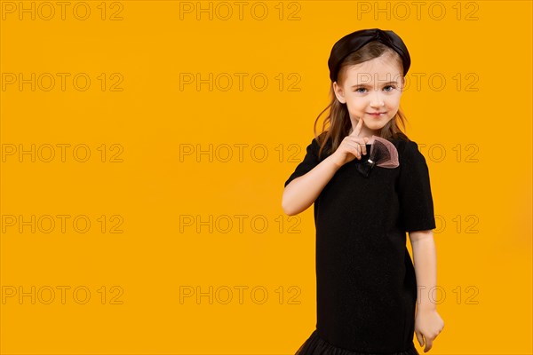 Cute young model girl in retro black tulle dress and hair band touching her chin