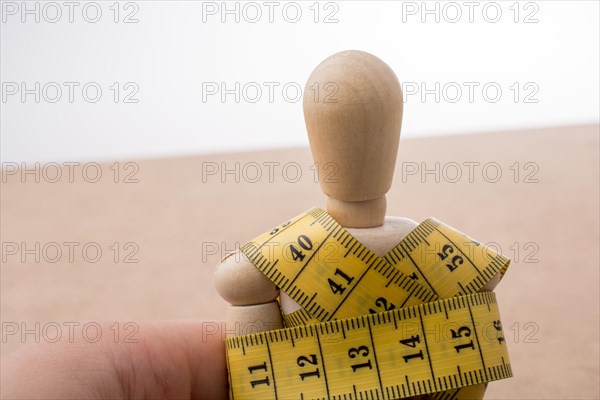 Yellow color measuring tape wrapped on wooden man