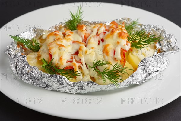 Closeup view of fried in foil sea fish and potato with paprika and cheese