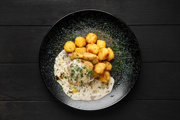 Top view of fried zander fillet with mushroom sauce and potato balls on a plate