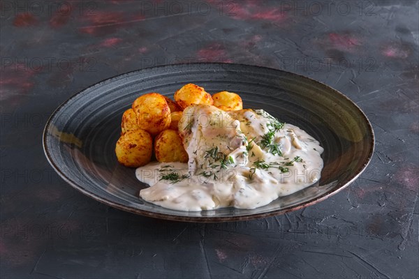 Fried potato balls and white fish fillet with creamy sauce