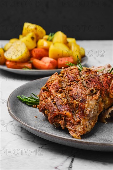 Closeup view of pulled lamb shoulder meat baked in oven with potato and carrot on marble table