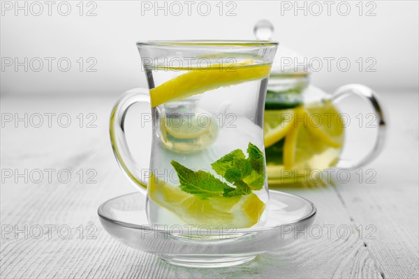 Antioxidant hot drink with lemon and mint in transparent tea pot and glass