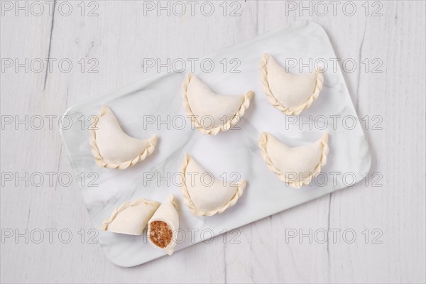 Top view of frozen dumplings stuffed with beef meat and provencal herbs on marble serving plate