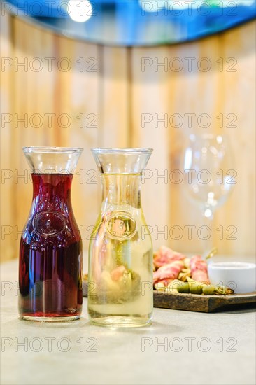 Two decanters with wine and plate with snack on background