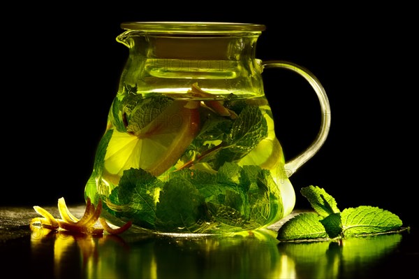 Transparent teapot of green tea with lemon and mint with ingredients. Jar of green tea with lime