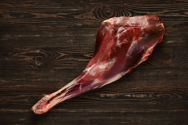 Overhead view of raw deer leg over wooden background