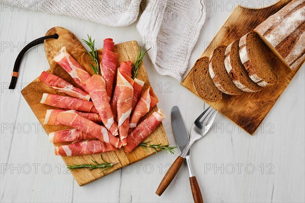 Overhead view of rolled slices of jamon on wooden cutting board