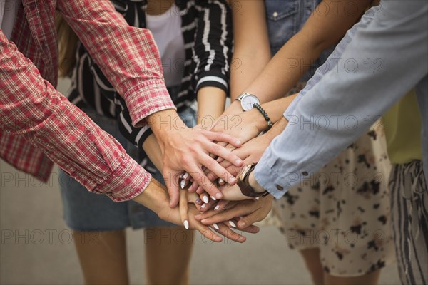 Close up friends putting hands top each other