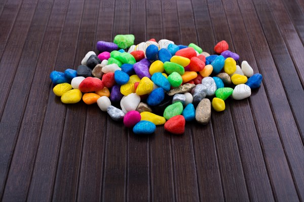 Pile of little colorful pebbles on wooden background