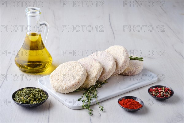 Semifinished beef patties in breading on a kitchen table