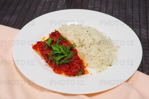 Fried with spices white sea fish served with rice and dill