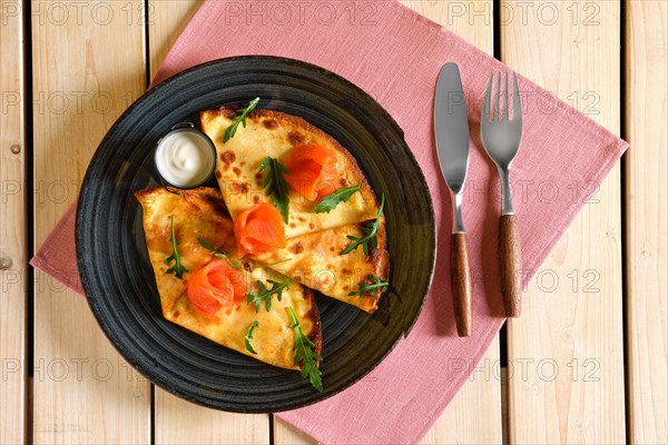 Top view of table with thin pancakes with salmon and sour cream