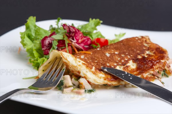 Cutting with knife omelet with ham and fresh vegetables